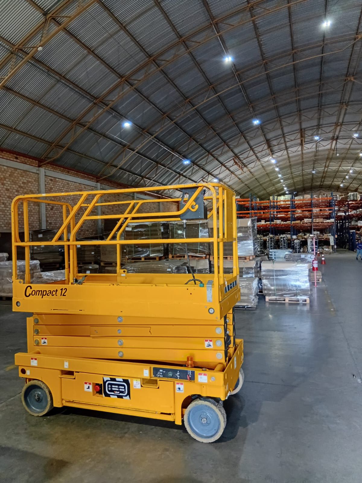 Plataforma tesoura Haulotte Compact 12 da SMV Rental em centro de distribuição